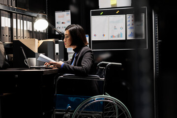 Paralyzed businesswoman employee in wheelchair checking bookkeeping analytical data documents....