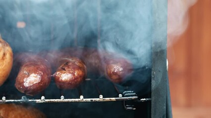 Sausage cooking in a smoker box outside 