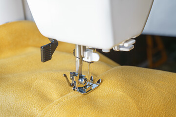 Modern sewing machine with yellow velours fabric. Sewing process clothes, curtains upholstery....