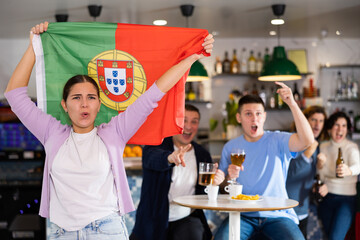 Fans with the flag of Portugal celebrate the victory of their favorite team in a beer bar