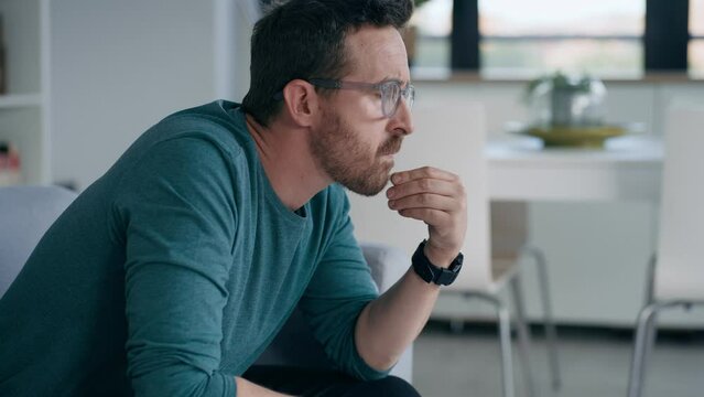 Video of worried mature man thinking about what he has read on his mobile phone while sitting on the couch at home