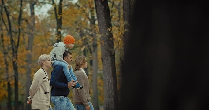 happy married couple and teenagers sons walking in park in autumn day, portrait, 4K, Prores