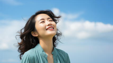 A Asian woman breathes calmly looking up isolated on clear blue sky