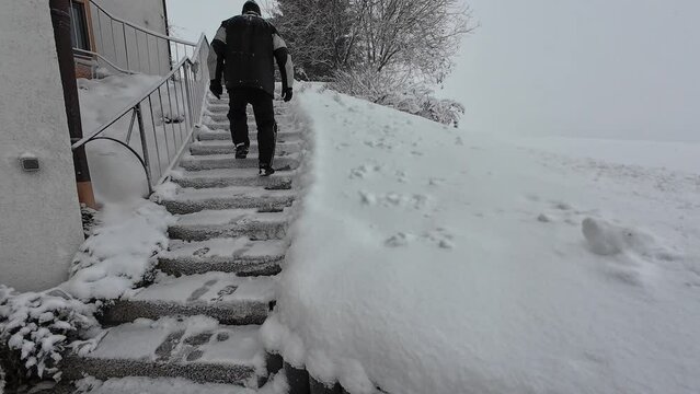Ein Mann geht im Winter eine schneebedeckte Treppe hinauf