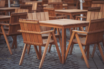 Coffeehouse cafe restaurant terrace. Wooden chairs and tables. Outdoor terrace concept. Shallow focus. Copy space. Old fashioned empty cafe terrace with vintage chairs and tables. Loft style cafe.
