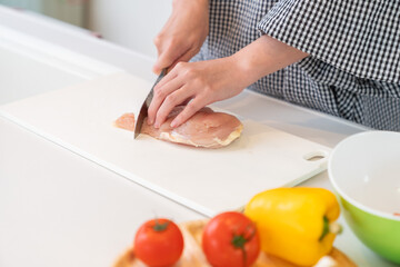 料理をする女性　手元　鶏肉を切る