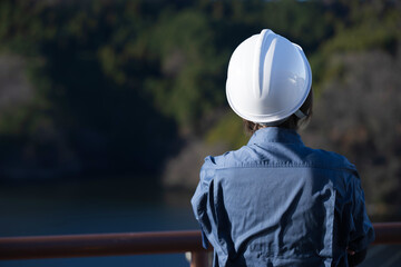 No back view of a middle-aged female site foreman staring into the future wearing a helmet, an...
