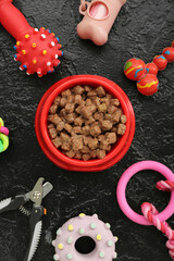 Composition with bowl of wet food and pet care accessories on dark background