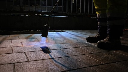 Night Time Roadworks Construction Site Worker Paver Using Burning Propane Gas Torch To Heat...