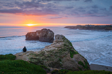 Person enjoying sunset in Natural Bridges State Beach of Santa Cruz, CA USA