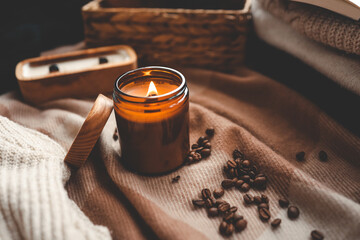 A burning candle with the smell of coffee, an open book and a stack of cozy sweaters, an aesthetic...