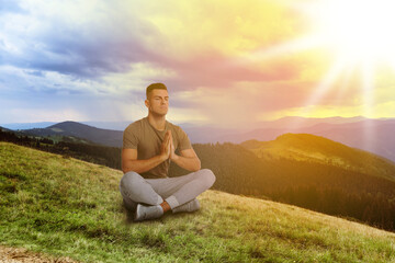 Fototapeta na wymiar Man meditating in mountains at sunrise, space for text