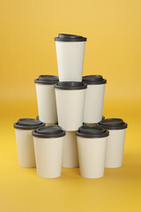 Disposable coffee cups stacked on yellow background. 3d illustration.