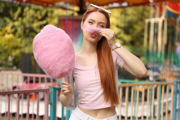 Beautiful woman having fun with cotton candy at funfair