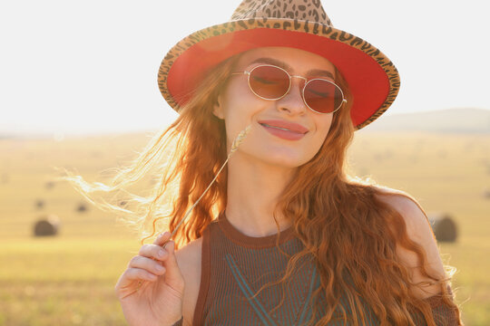 Beautiful happy hippie woman with spikelet in field