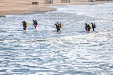 Ten tactical divers, frogmen, enter the sea from the beach	