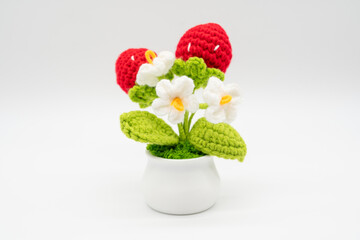 Strawberry and white flower knitted with crochet on a white background.