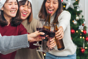 Christmas party Group of Asian Woman drink beer champagne exchange christmas gift box under xmas tree. Young women enjoy laughing sitting party together living room to celebrate Christmas holiday