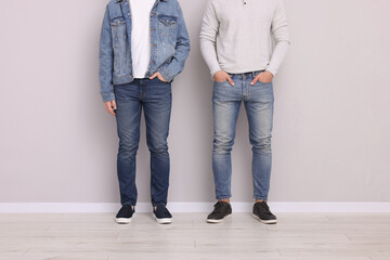 Men in stylish jeans near light grey wall indoors, closeup