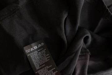 Clothing label in different languages on black garment, closeup