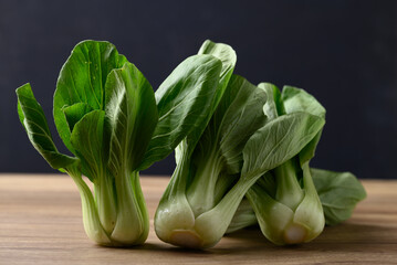 Bok choy or Pak choi (Chinese cabbage) on wooden table with black background, Organic vegetables