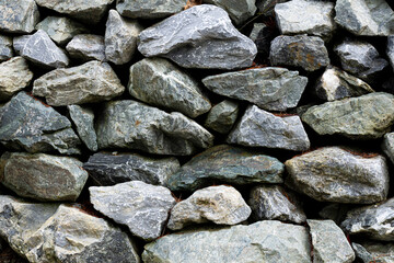 An abstract image of stacked grey stones to create a rustic retaining wall. 