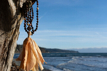 A peaceful image of a wooden mala necklace with peach colored silk tassel hanging for a driftwood...