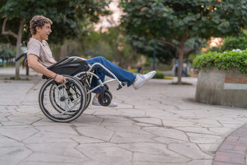Playful young man in wheelchair doing acrobatic trick - obrazy, fototapety, plakaty
