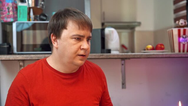 Portrait of greedy man in kitchen sighs in fear, extends hand with money, one hundred euros, gives it away with regret Henpecked husband gives wife his salary, nest egg for family budget Life