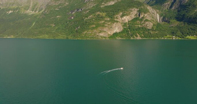 Drone tracking follows watercraft speeding and turning in green water of Lustra Fjorden Fjord Norway