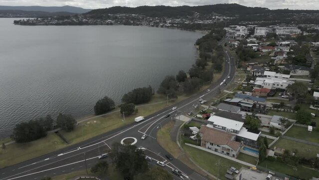 Vehicle traffic on seaside street beside Warners Bay in NSW, Australia
