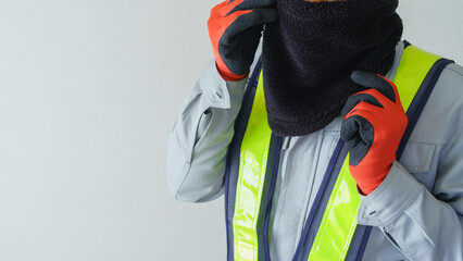 ネックウォーマーで防寒対策をする作業服の男性