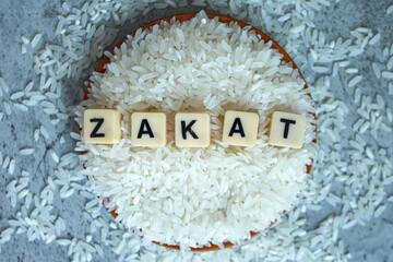 Top view of Zakat word on rice grain in wooden bowl. Islamic zakat fitrah concept
