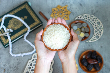 Portrait of muslim hands holding a bowl of rice grain with Islamic decoration on the background,...