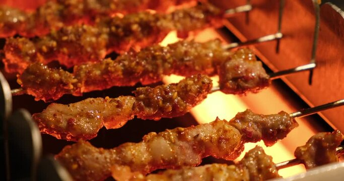 close up cooking several mutton shashlik rotating on automatic barbecue grill