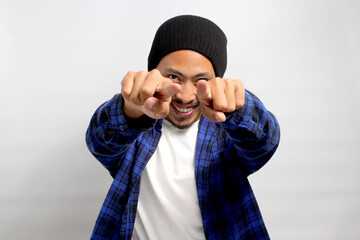An excited young Asian man is smiling warmly and pointing his finger towards the camera, indicating...
