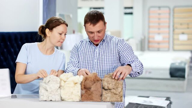 Interested positive couple, man and woman, selecting breathable, hypoallergenic filler for softness and volume of sofa, pillows or comforters in furniture store. High quality 4k footage