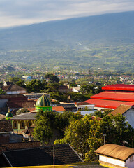 View of the city of Batu in East Java, Indonesia. In the background, there are mountains and a mosque with a green dome.