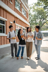 Group of diverse happy Asian college students are enjoying talking after classes on a footpath.