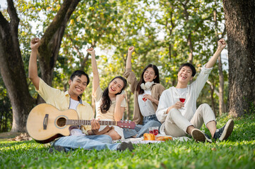 A group of cheerful Asian friends is enjoying a picnic in a public park on a summer day together.