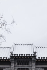 Rooftop of Chinese traditional building against sky with snow. Beijing, China