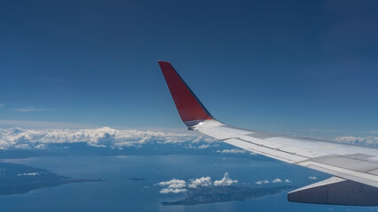 The aerial view from the plane to Malaysia. Tropical islands in the blue ocean. Clouds in the azure sky.  The wing of the aircraft is in the foreground. Copy space. 