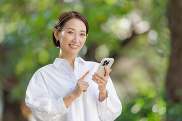 女性　スマートフォン　新緑