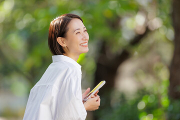 女性　スマートフォン　新緑