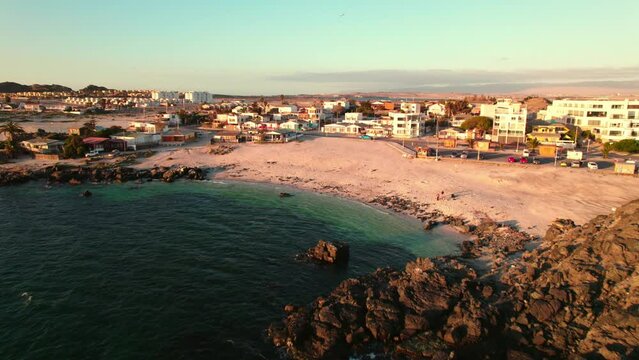 Aerial view dolly in on the beach of Bahia Inglesa in the Coquimbo region with orange colors and crystal clear waters at sunset.