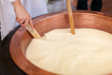 Diary Farm Close Up of Cheese Making Artistry: Hands expertly blend Milk, Cultures, and Rennet in Heating All Together in a Copper Boiler, Crafting Artisanal Dairy Product - Cheese
