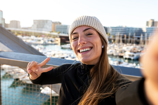 Young happy jogger woman taking selfie while running outdoors during winter in the city. Female runner looking at camera