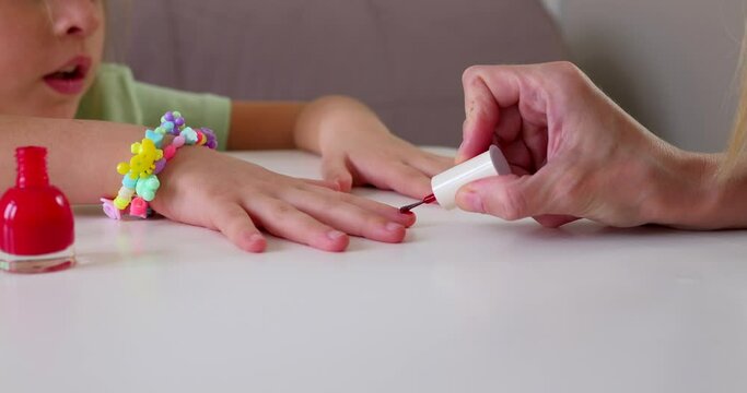 Mother paints her little daughters on the table, beauty ritual
