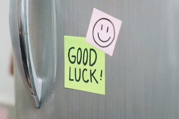 Sticky notes with Good Luck text on refrigerator door in kitchen.