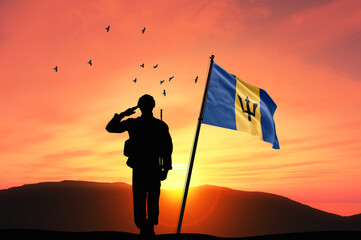 Silhouette of a soldier with the Barbados flag stands against the background of a sunset or sunrise. Concept of national holidays. Commemoration Day.